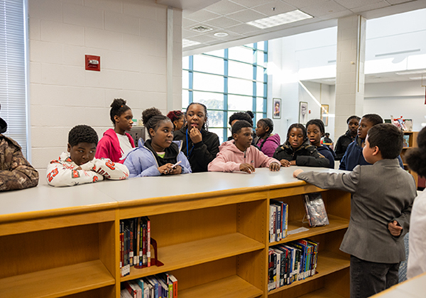 Student groups standing at library counter to tour Huntington Middle School's living wax museum for Black History Month